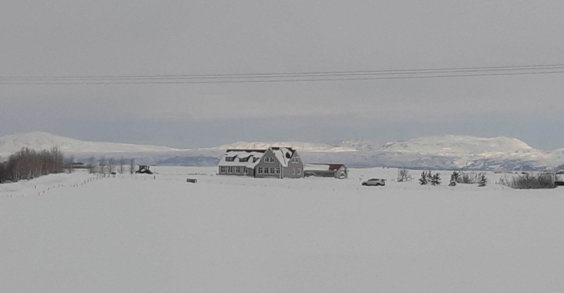 A rural landscape with a farmhouse and a car parked nearby.