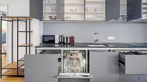 Une cuisine moderne avec des meubles de couleur grise, un lave-vaisselle encastré, un four à micro-ondes et un évier.