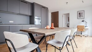 Une cuisine moderne avec des meubles gris, une table à manger en bois et des chaises blanches.