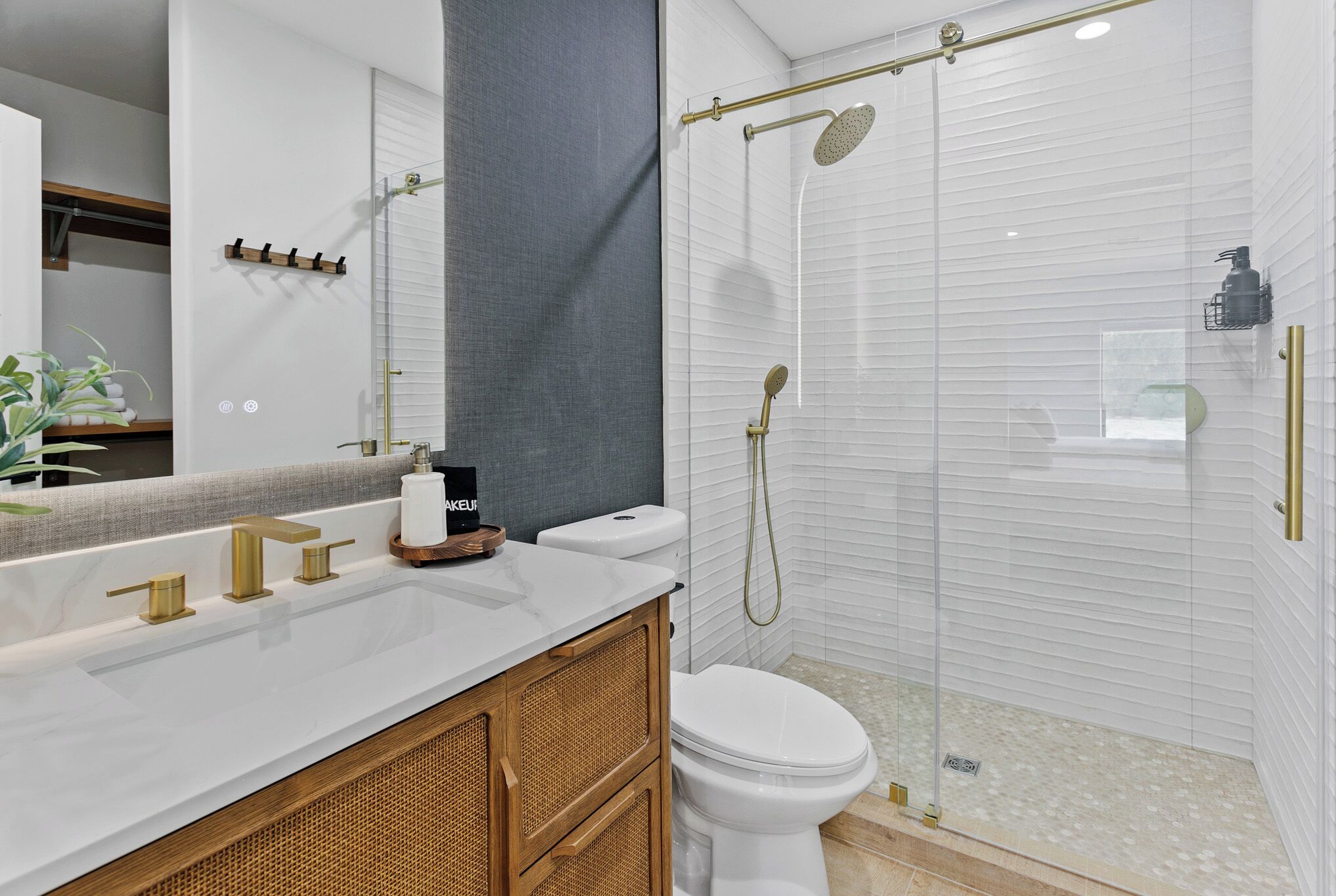 Een badkamer met een witte wasbak, gouden kraanwerk, een toilet en een douchecabine met glazen wanden.