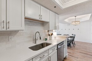Una cucina moderna con mobili bianchi, un lavello in acciaio inossidabile e una lavastoviglie integrata.