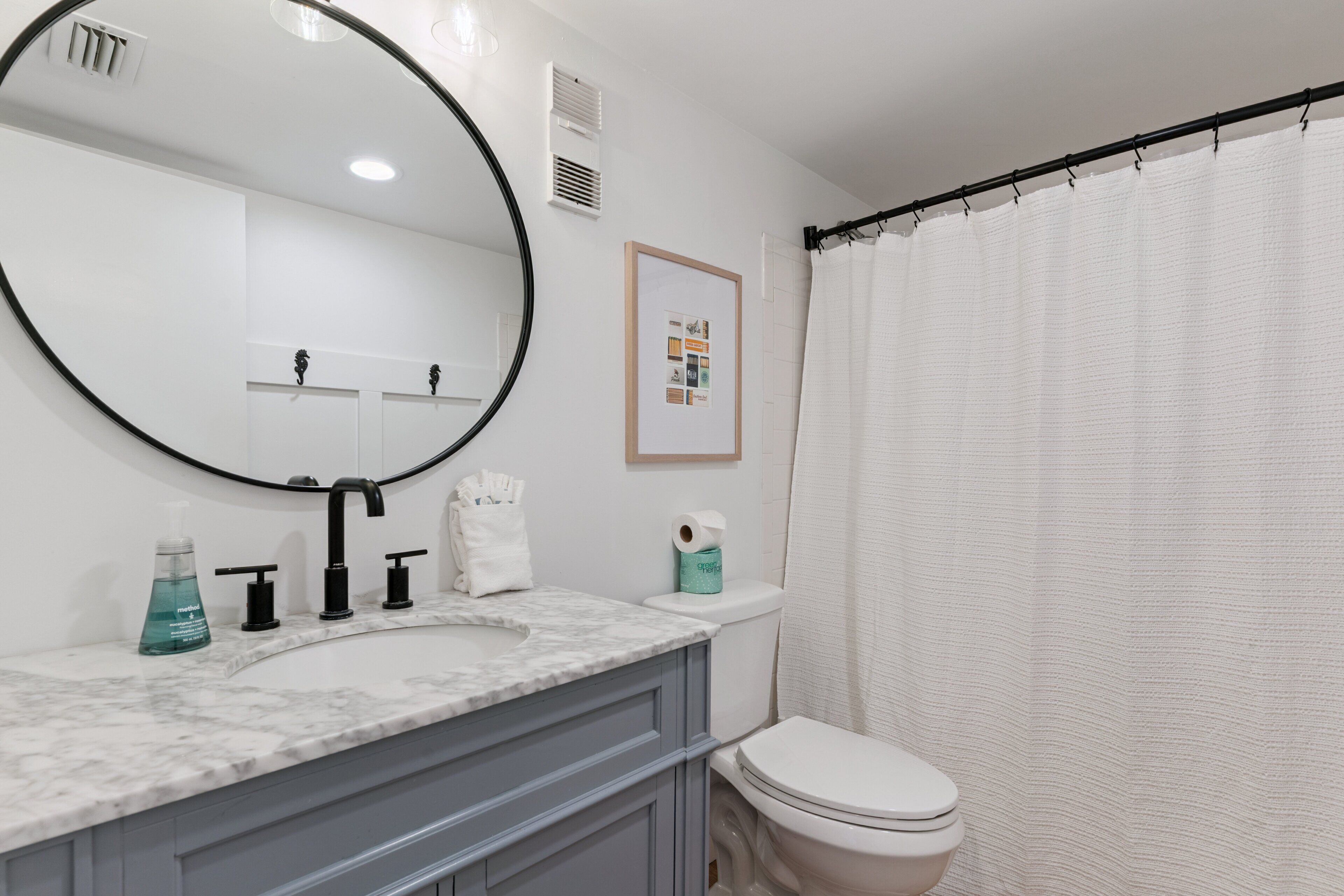 A bathroom with a marble sink, a large mirror, a toilet, and a shower curtain.