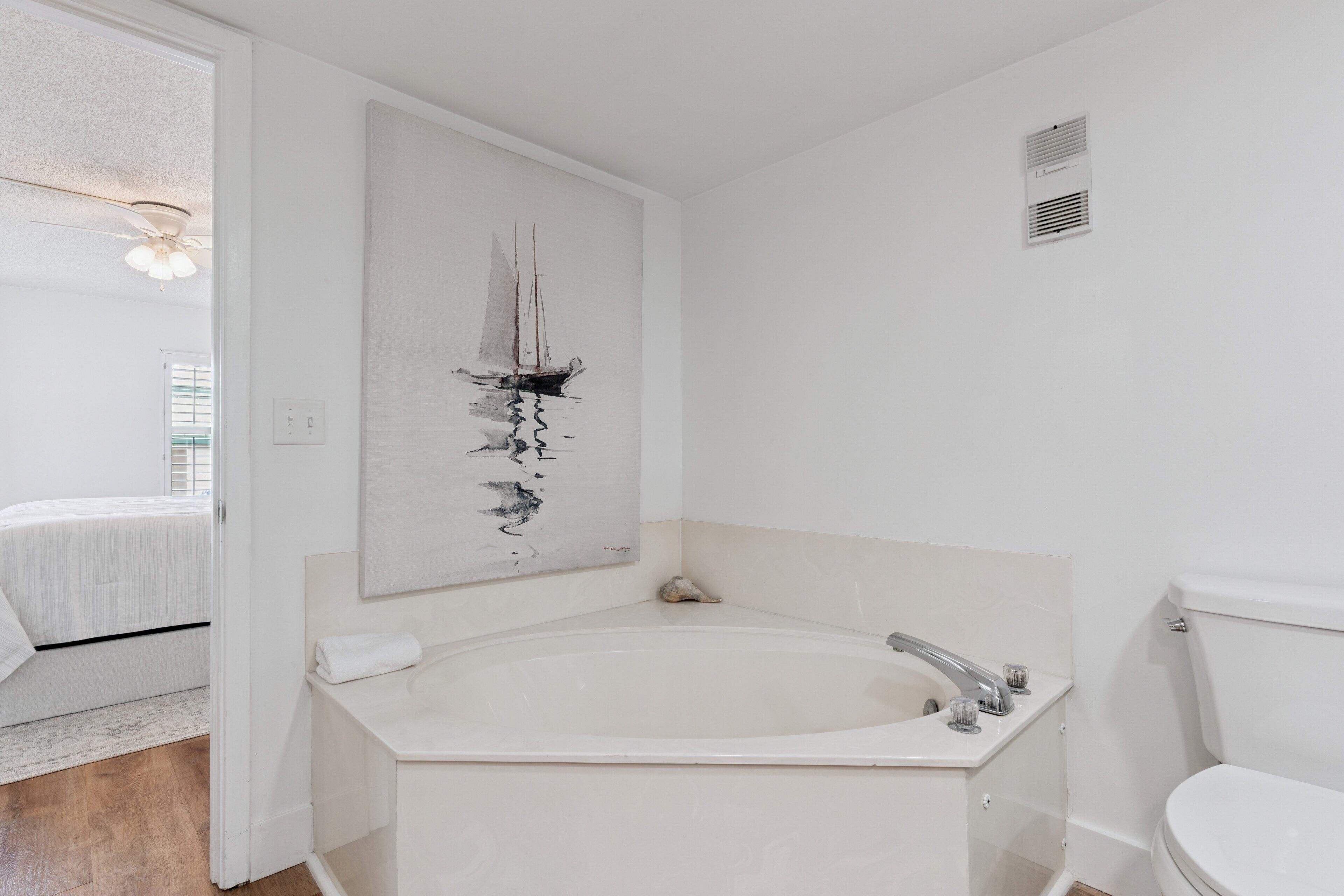 A modern bathroom with a freestanding bathtub, a toilet, and a wall-mounted artwork.