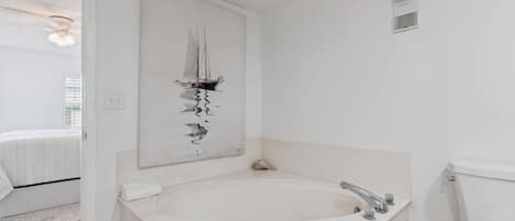 A modern bathroom with a freestanding bathtub, a toilet, and a wall-mounted artwork.