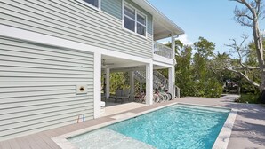 A two-story house with a swimming pool, outdoor seating, and a covered porch. - Salt + Sol | Heated Pool |Canal-Front | Golf Cart | Dock (Anna Maria)