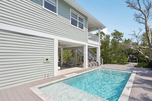 A two-story house with a swimming pool, outdoor seating, and a covered porch. - Salt + Sol | Heated Pool |Canal-Front | Golf Cart | Dock (Anna Maria)