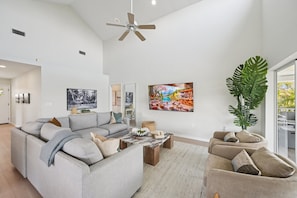 A spacious living room with a sectional sofa, a coffee table, and a large plant. - Salt + Sol | Heated Pool |Canal-Front | Golf Cart | Dock (Anna Maria)