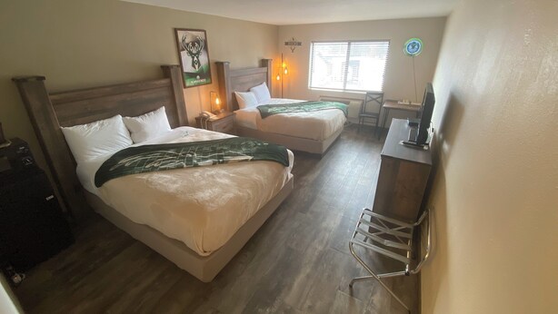 A hotel room with two beds, a desk, a chair, a clock, and a window with blinds. - Pioneer Motor inn (Westfield)
