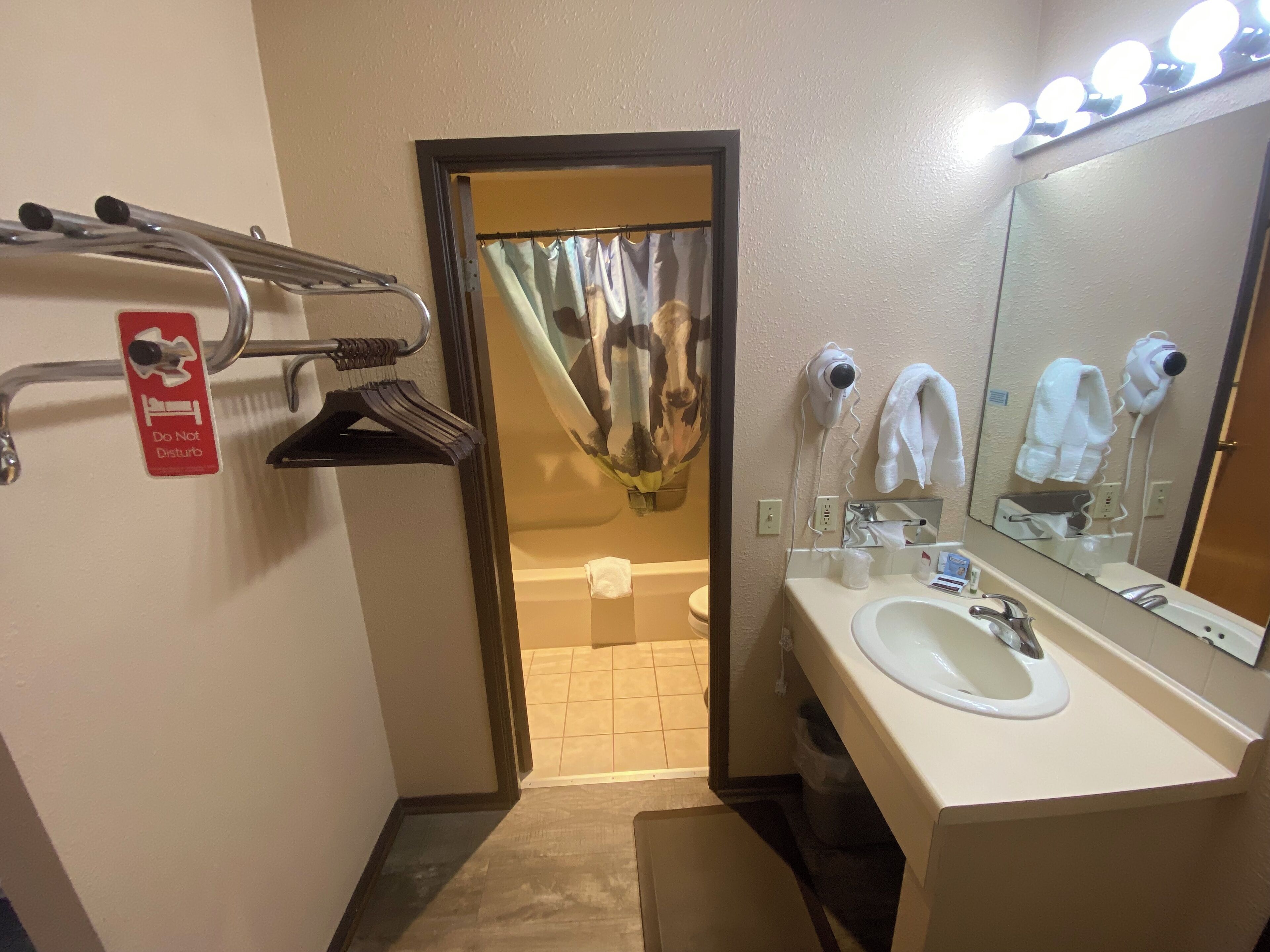 A bathroom with a sink, mirror, towel rack, and a sign that reads "Do Not Disturb."