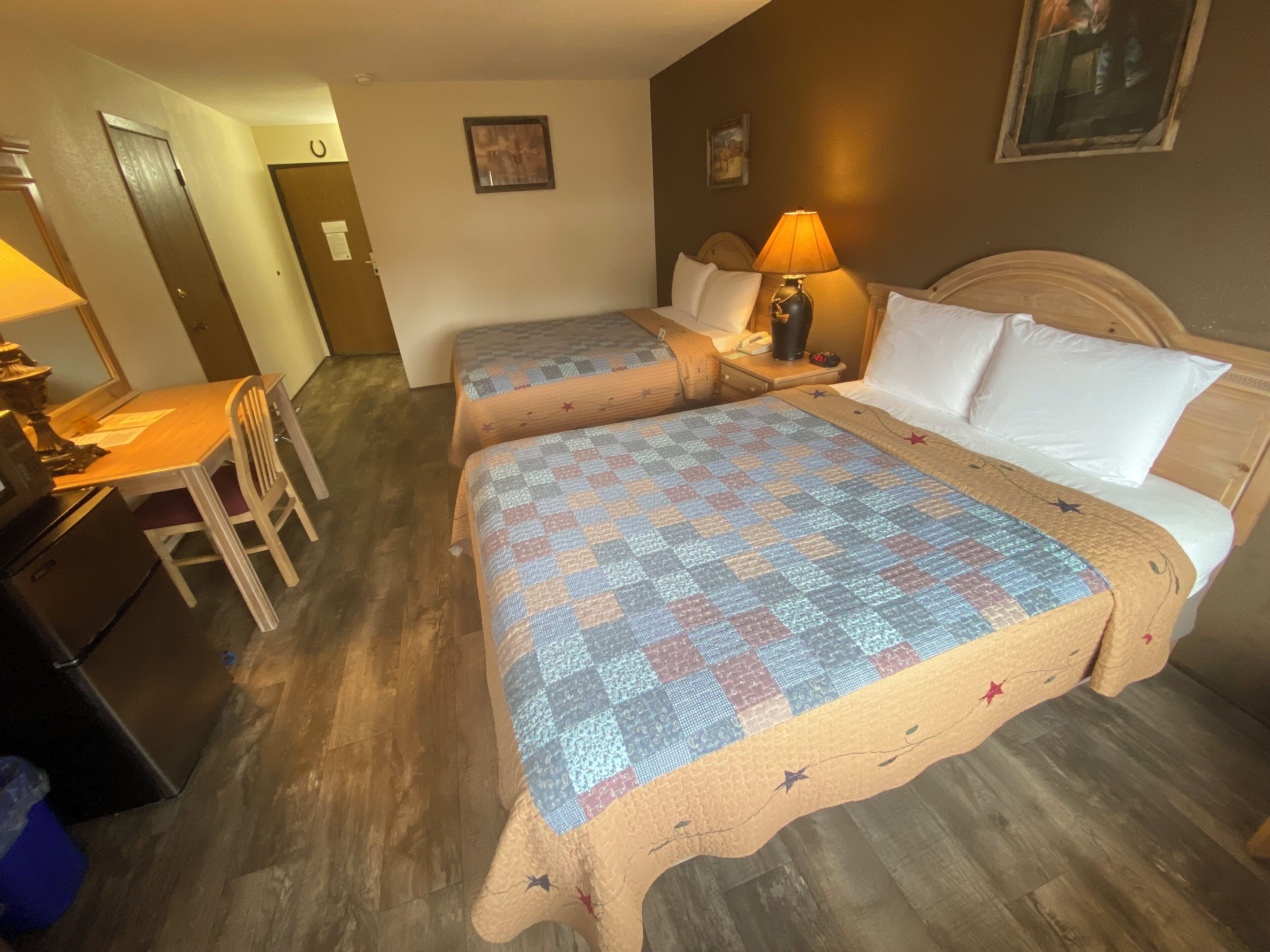 A hotel room with two beds, a desk, and a chair.