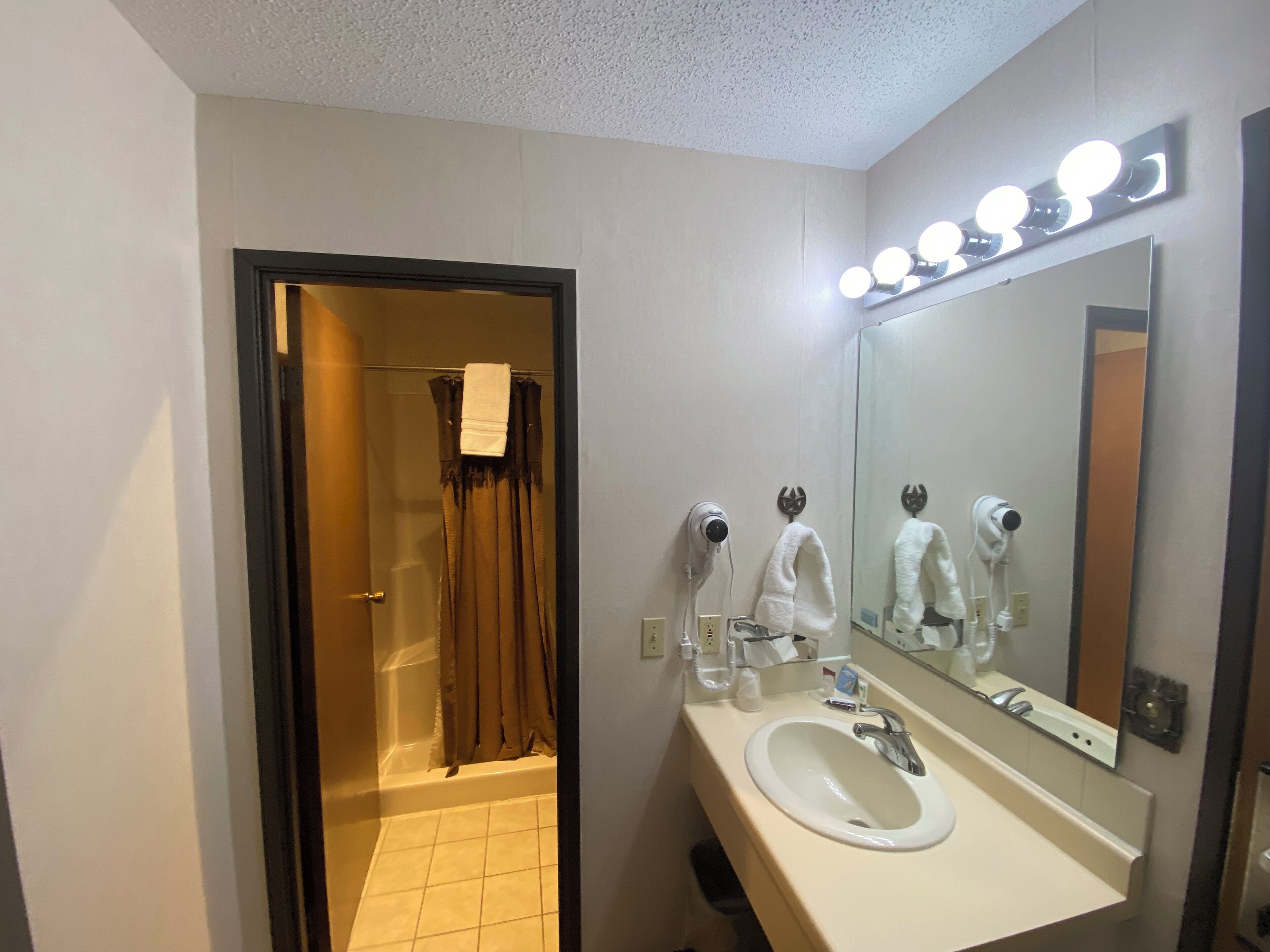 A bathroom with a sink, mirror, and lights above the mirror.
