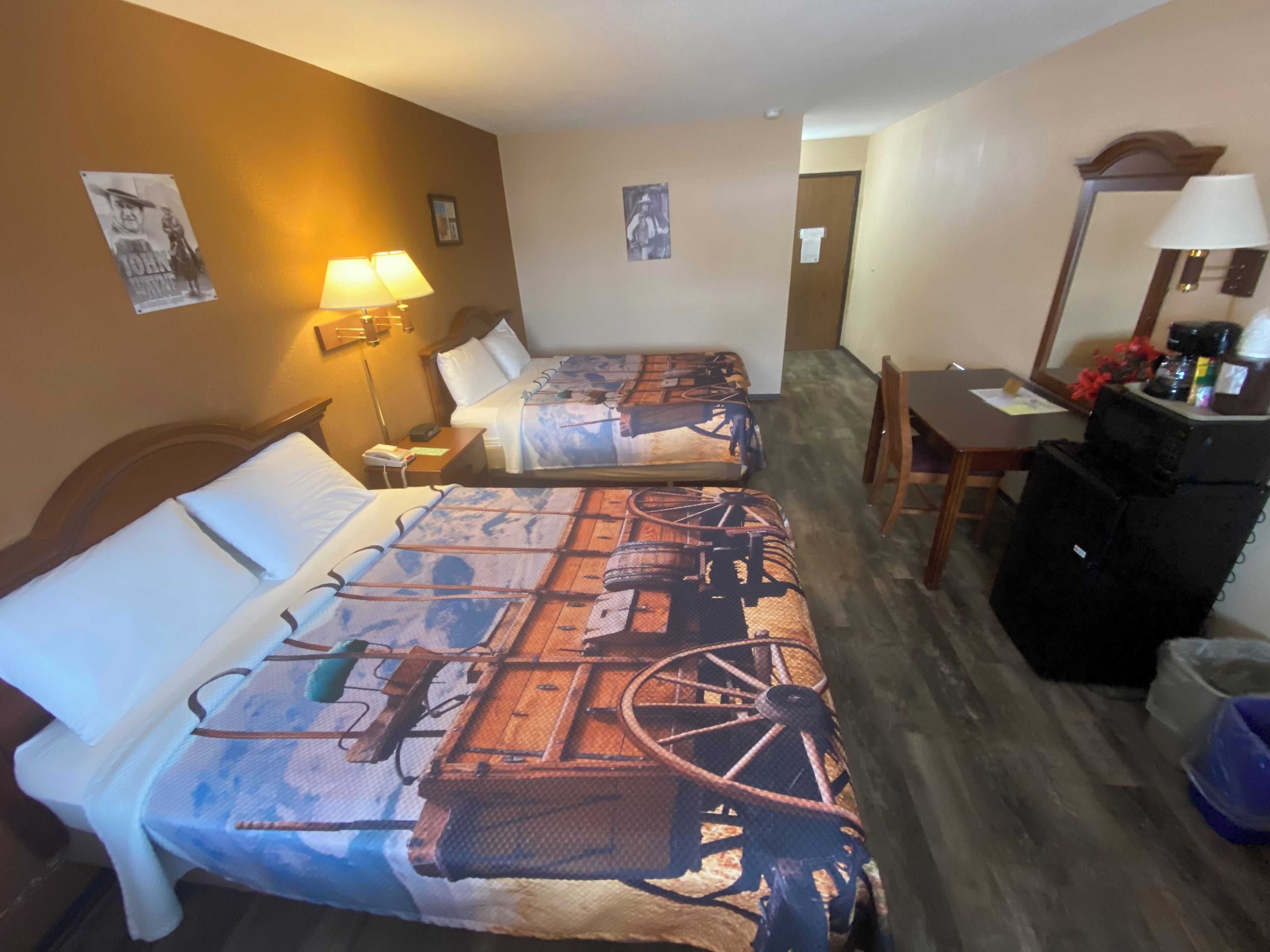 Ein Hotelzimmer mit zwei Betten, einem Schreibtisch, einem Stuhl und einer Kaffeemaschine.