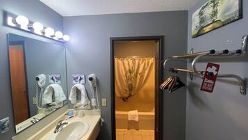 Un baño con lavamanos, espejo, secador de pelo y toallero.