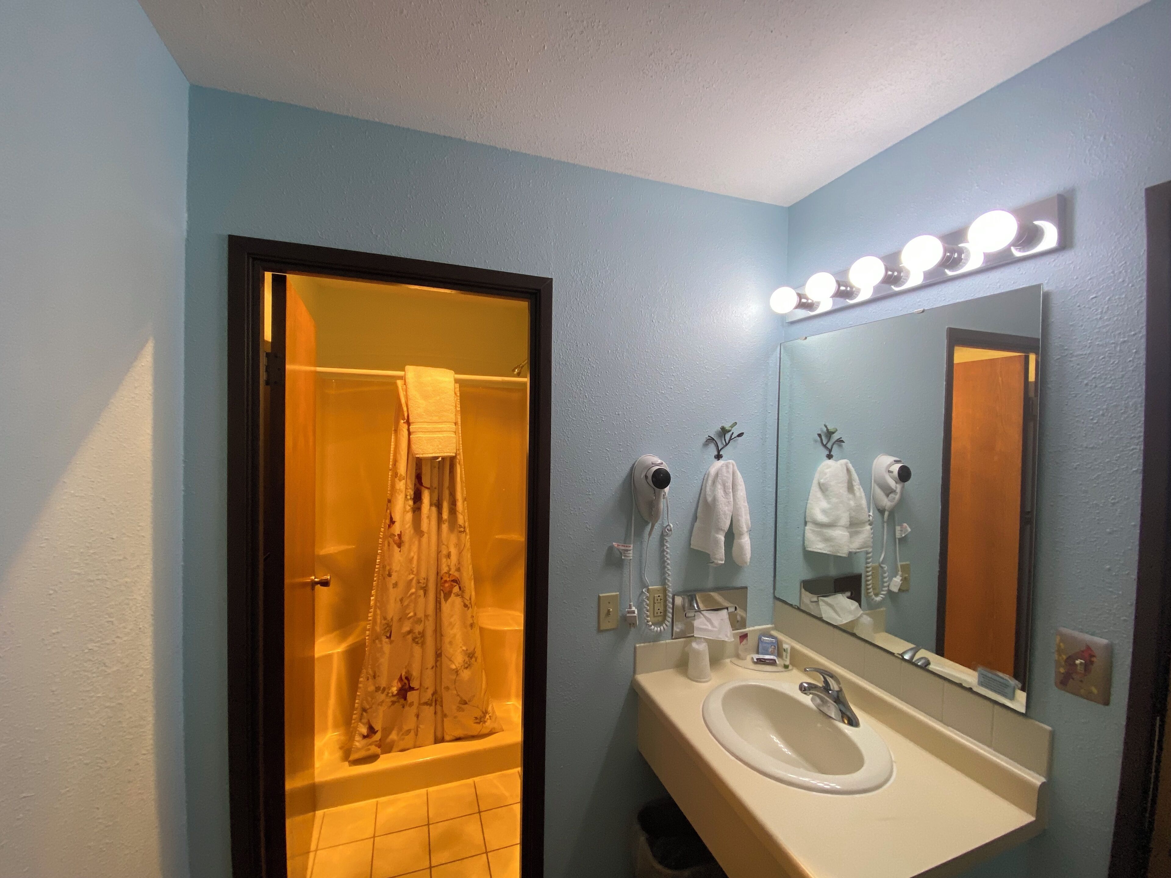 Un baño con bañera, lavabo y espejo con iluminación.