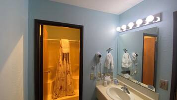 Un baño con bañera, lavabo y espejo con iluminación.
