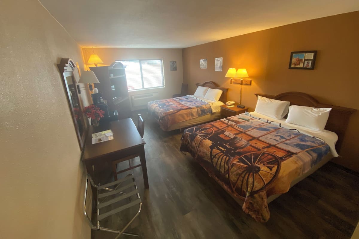 Una habitación de hotel con dos camas, un escritorio, una silla y un aparador.