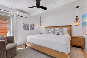 Un dormitorio moderno con una cama grande, un ventilador de techo y vista al océano.