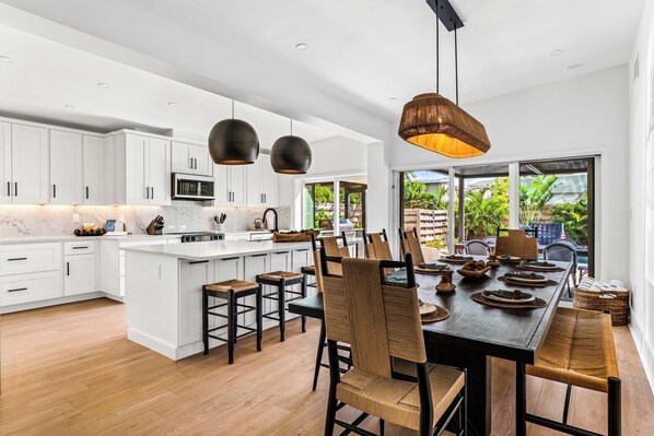 A modern kitchen with white cabinets, a central island, and a dining area with a large table and chairs.