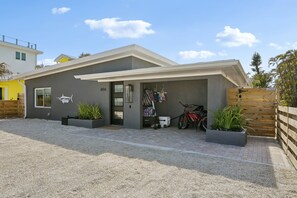 A modern two-story house with a covered garage, a number '866' on the wall, and two potted plants in the driveway. - Rod and Reel Retreat | Heated Pool & Spa | Steps to Beach | Golf Cart (Anna Maria)