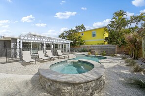 A backyard with a swimming pool, lounge chairs, and a covered patio area. - Rod and Reel Retreat | Heated Pool & Spa | Steps to Beach | Golf Cart (Anna Maria)