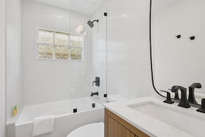 A modern bathroom with a bathtub, a shower, and a sink. - Rod and Reel Retreat | Heated Pool & Spa | Steps to Beach | Golf Cart (Anna Maria)