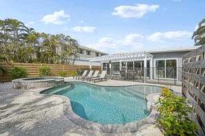 A swimming pool with lounge chairs and a covered patio area. - Rod and Reel Retreat | Heated Pool & Spa | Steps to Beach | Golf Cart (Anna Maria)