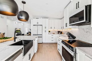 Eine moderne Küche mit weißen Schränken, einer Edelstahl-Spüle, einem eingebauten Backofen und einer Mikrowelle.