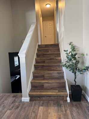 Un escalier avec des marches en bois et des rampes blanches, menant à une porte située en haut.