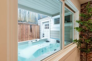 Ein Whirlpool vor einem Haus mit Holzzaun und Backsteinmauer.