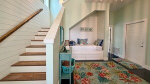 A staircase with wooden steps and white railings, leading to a bedroom with a bed, a nightstand, and a wall-mounted lamp. - Private Pool, Shared Pool, Boardwalk to the Beach (Port Aransas)