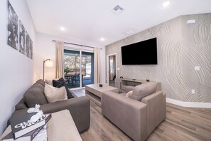 Una sala de estar moderna con un sofá, una mesa de centro y un televisor de pantalla plana montado en la pared.