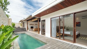 A modern house with a swimming pool, wooden deck, and a bedroom with a bed and curtains. - Villa Ivory 8Min Beach Pecatu byOrivista (Pecatu)