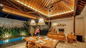 An outdoor dining area with a pool, wooden furniture, and a ceiling fan. - Villa Ivory 8Min Beach Pecatu byOrivista (Pecatu)