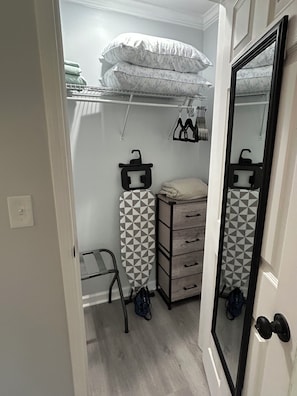 A compact walk-in closet with a mirrored wardrobe, a hanging rack, and a storage unit.