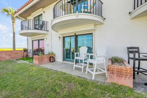A two-story house with a balcony, a patio with outdoor furniture, and a small garden area. - NEW Pet friendly 2/2 townhouse, Beachfront property with a seasonally heated pool (Flagler Beach)