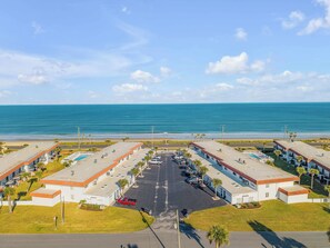 A coastal hotel with a parking lot, multiple buildings, and a view of the ocean. - NEW Pet friendly 2/2 townhouse, Beachfront property with a seasonally heated pool (Flagler Beach)