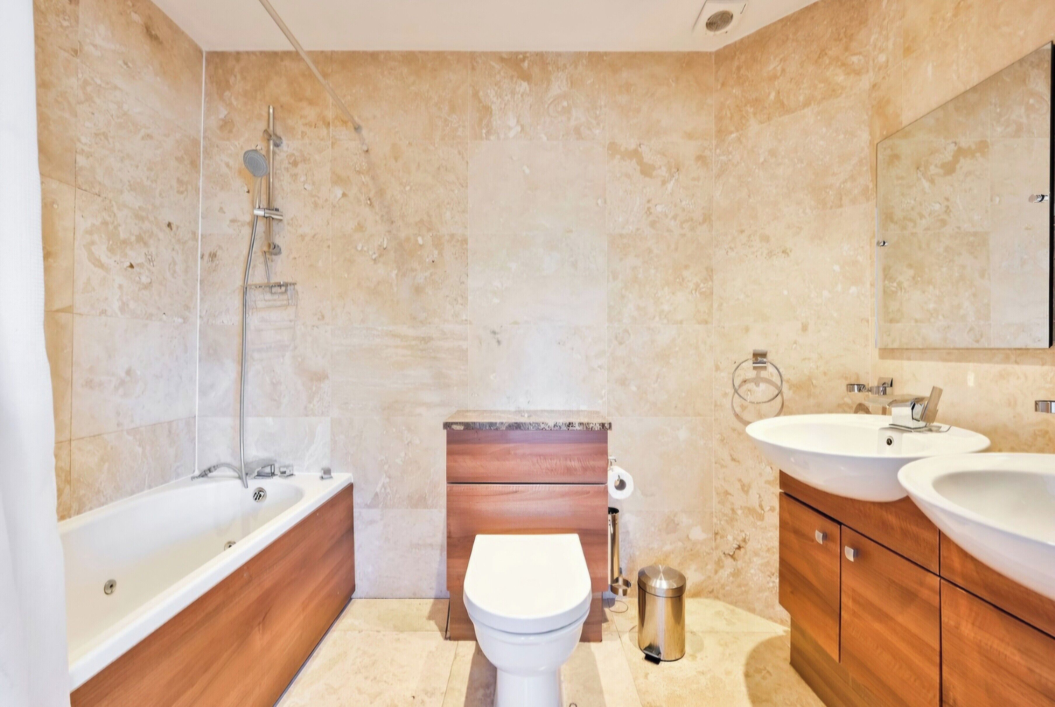 Un baño moderno con bañera, inodoro e lavamanos dobles.