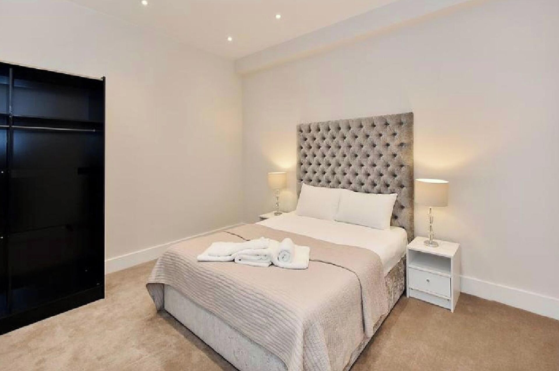 A neatly arranged bedroom with a large bed, a bedside table, and a wardrobe.