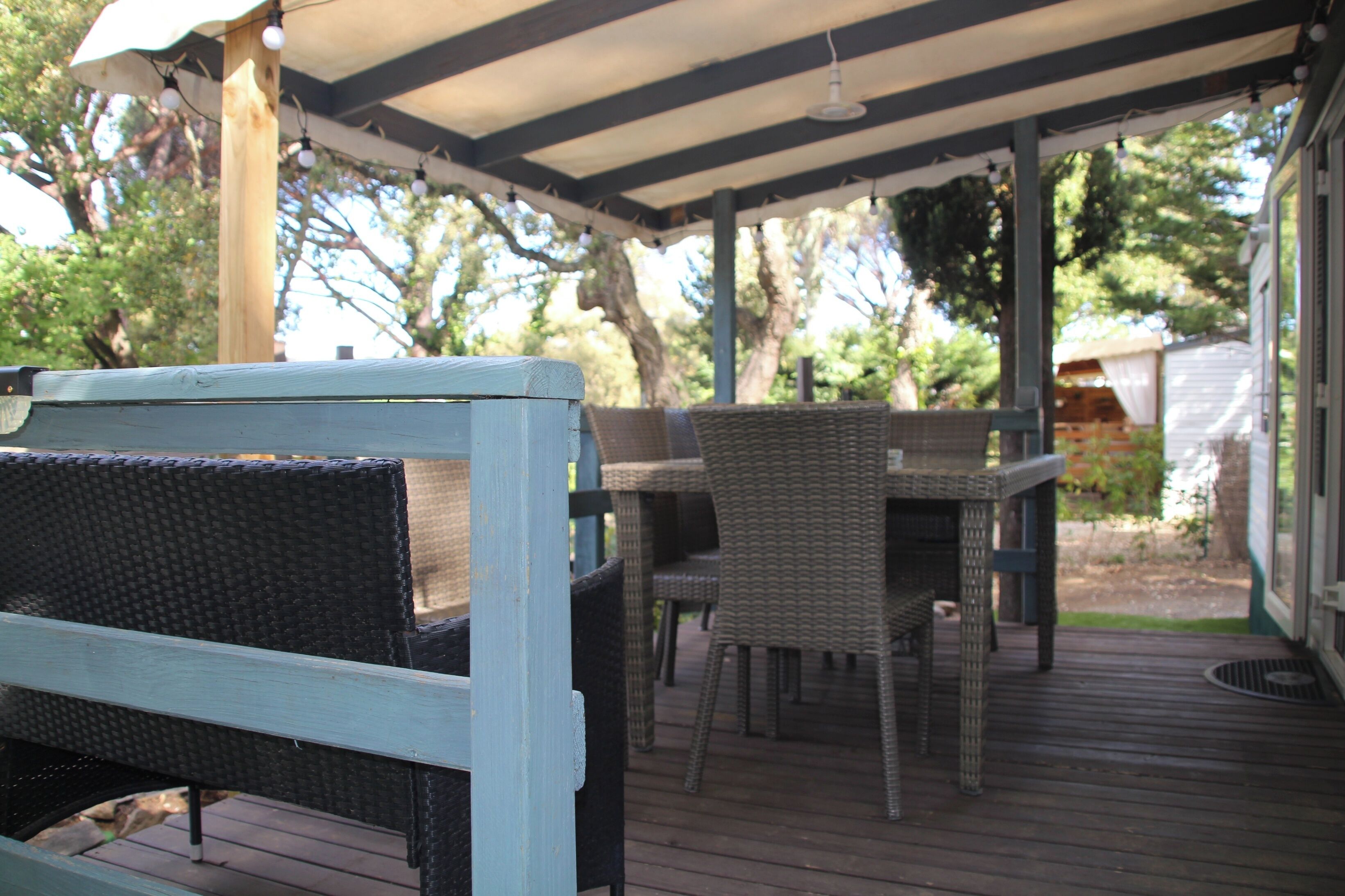 An outdoor patio with wicker furniture, a covered area, and a view of the backyard.