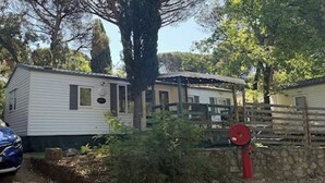 Una casa mobile con un cortile recintato, una cassetta delle lettere rossa e un albero sullo sfondo.