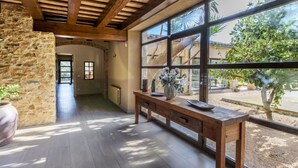 A spacious room with a stone wall, wooden ceiling beams, and large windows offering a view of the outdoors. - El Refugio Mediterráneo by Interhome (Begur)