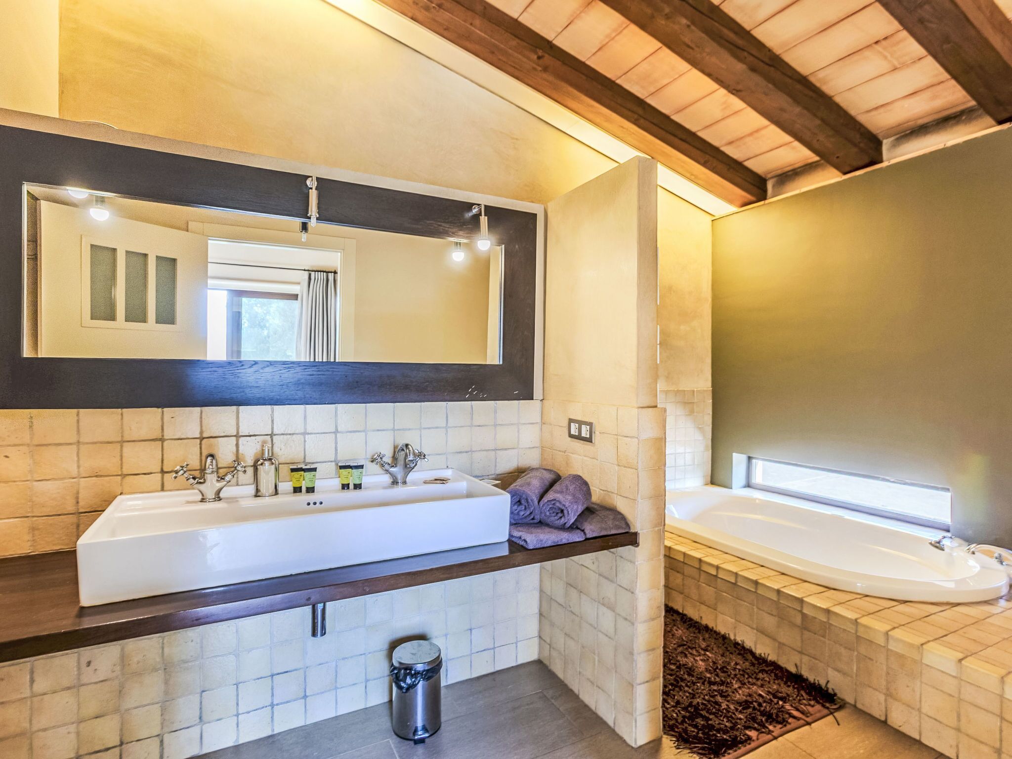 Une salle de bain moderne avec un grand lavabo blanc, une baignoire et un plafond en bois foncé.