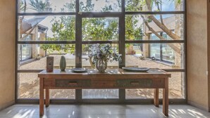 A room with a large window, a wooden table, and a vase with flowers. - El Refugio Mediterráneo by Interhome (Begur)