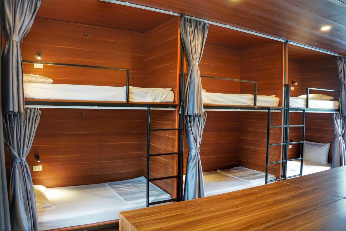 Eine Holzhütte mit Etagenbetten, Holzwänden, Vorhängen und einem Holztisch.