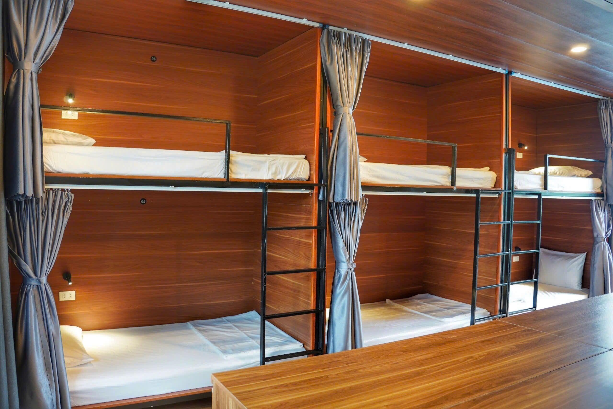 Een slaapkamer met stapelbedden, houten wanden en gordijnen.