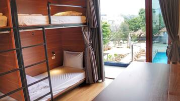 A bunk bed room with a view of a pool and outdoor seating.