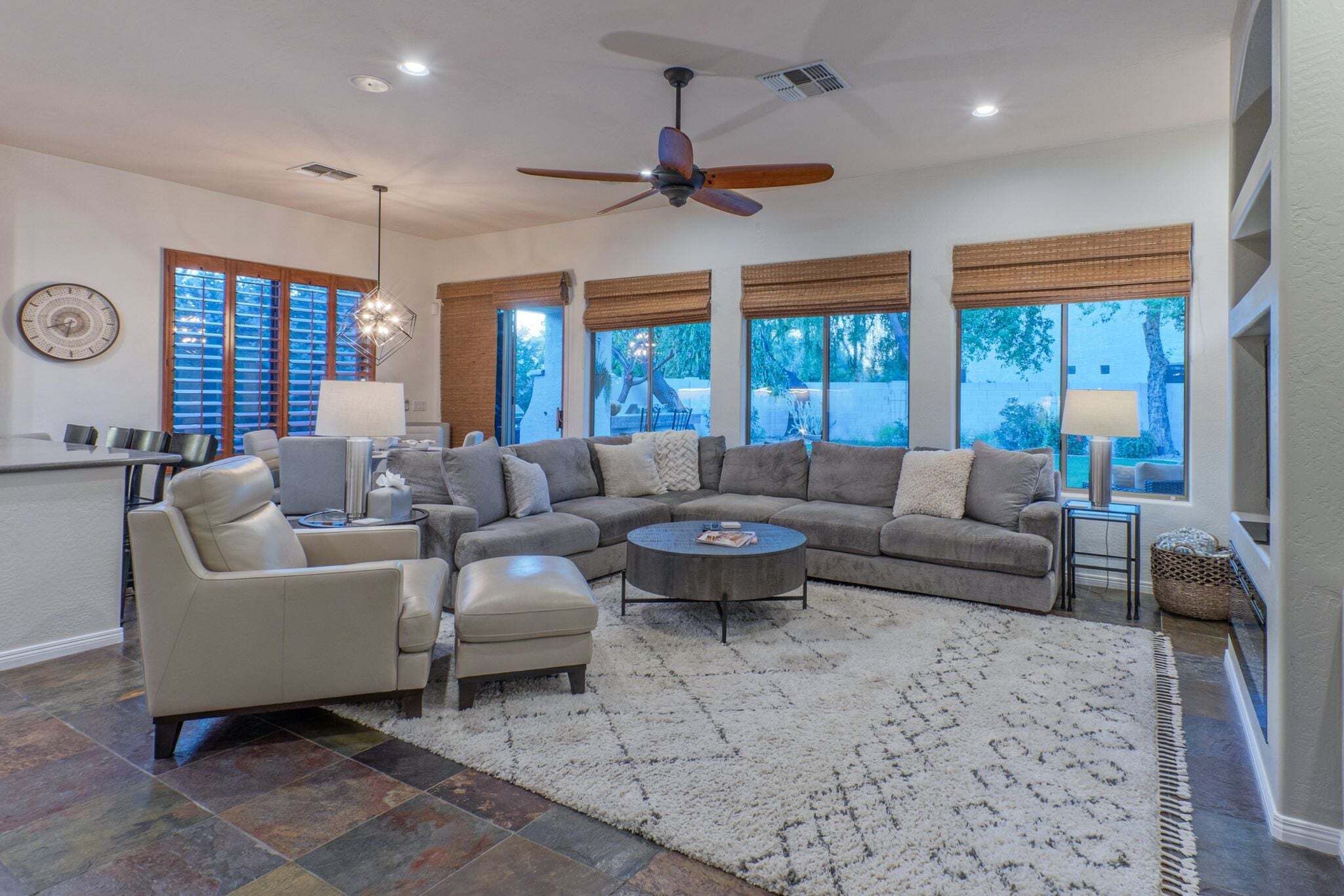 A spacious living room with a sectional sofa, a round coffee table, and a ceiling fan.
