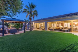 A residential property with a covered patio, outdoor seating, and a well-maintained lawn.