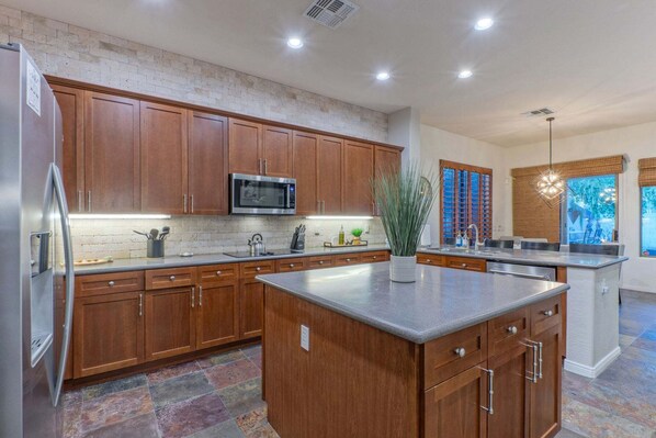 A modern kitchen with wooden cabinets, a central island, a microwave, and a sink.