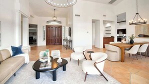 A spacious living room with a round coffee table, a dining area with a wooden table and chairs, and a kitchen in the background. - Princess Views-Pool & Spa-Walk to TPC Scottsdale (Scottsdale)